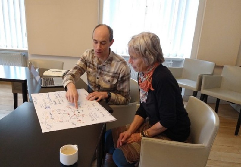 Two people sitting at a table with a box of pizzaDescription automatically generated with low confidence